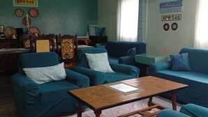 Ein Wohnzimmer mit türkisfarbenen Sofas, einem Holztisch und einem gemusterten Teppich.