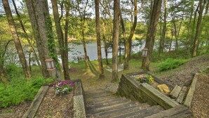 A wooden staircase leading down to a river, surrounded by trees and a lantern. - Lakeside Cabin w/ mountain views, dock, fire pit, hot tub, and much more! (Ellijay)