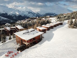 Ein schneebedecktes Bergresort mit Holzhütten und einer Skipiste.