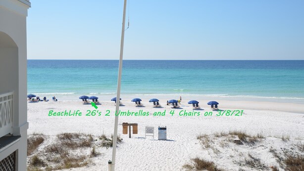 Een uitzicht op het strand met parasols en stoelen.