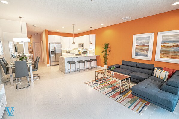 A modern living room with a grey sofa, a coffee table, and a dining area with a glass table and chairs. - Kids-Friendly, Family-Friendly 3BD Deluxe Townhome 1603 (Clermont)
