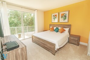 A bedroom with a large bed, two nightstands, a wooden desk, and a balcony with a view of trees. - Kids-Friendly, Family-Friendly 3BD Deluxe Townhome 1603 (Clermont)