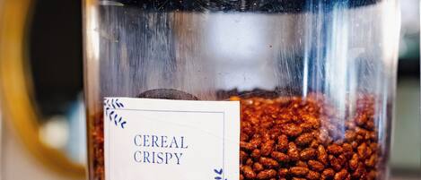 Un recipiente de vidrio etiquetado 'Cereal Crispy' lleno de hojuelas de cereal.