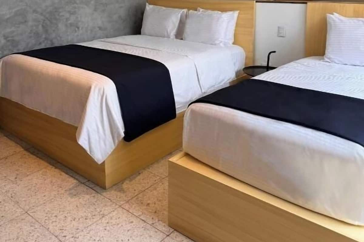 A hotel room with two beds, a TV, and a wardrobe.