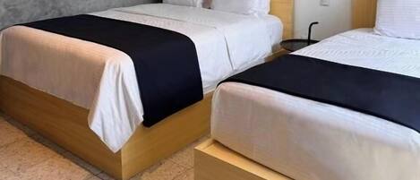 Une chambre d’hôtel avec deux lits, une télévision et une armoire.