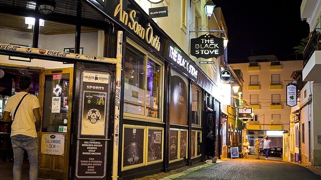 Una calle estrecha con un pub llamado "An Sorn Ough" y "The Black Stove" a la derecha.