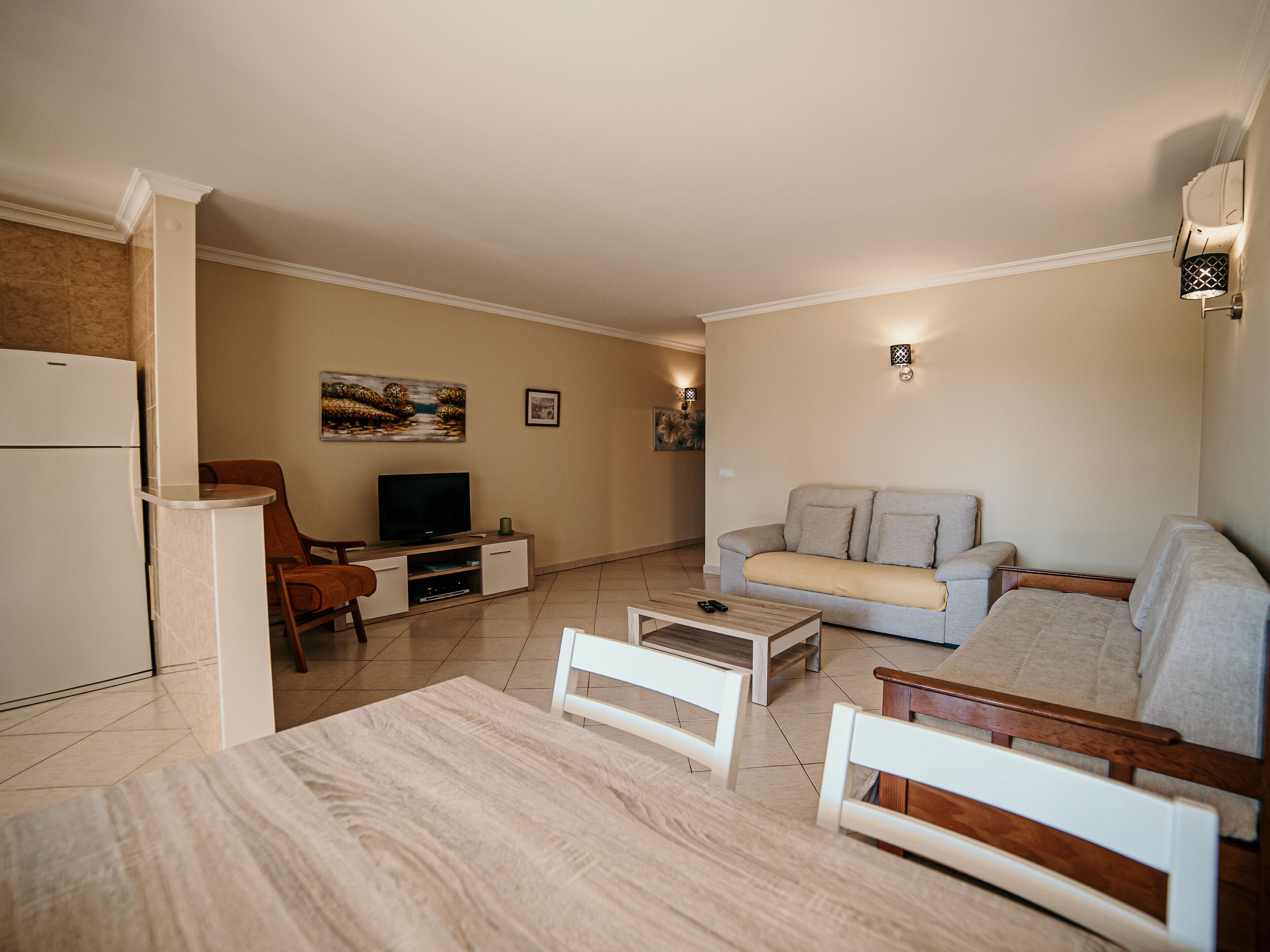 A modern living room with a sofa, a TV, a coffee table, and a dining table.