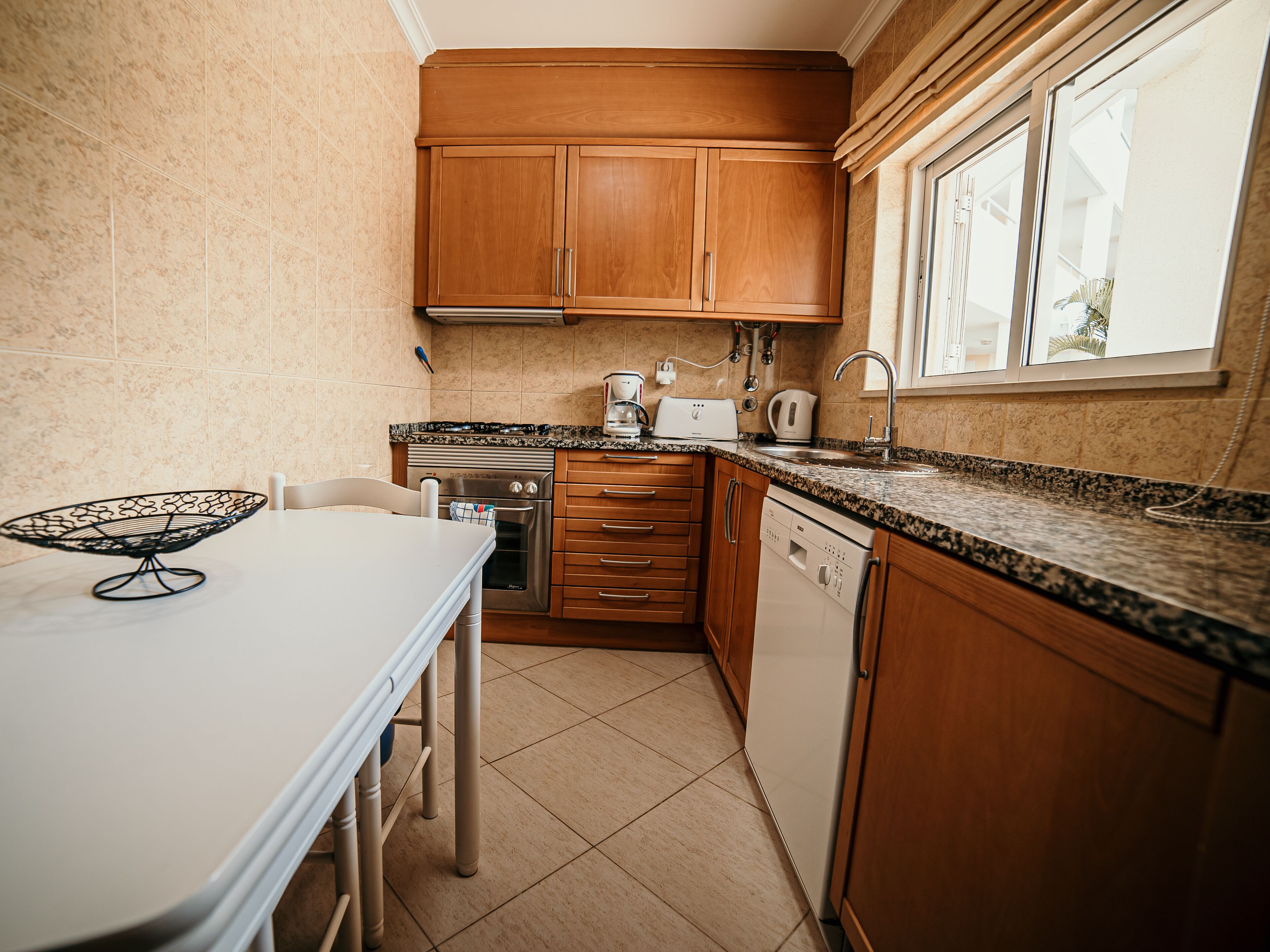 A kitchen with wooden cabinets, a countertop, a sink, a stove, and a dishwasher.