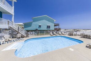 A swimming pool area with a two-story building, outdoor seating, and a view of the beach. - Beachfront/Pool! 5 bedroom! Book Now and Save!*Sleeps 12* (Gulf Shores)