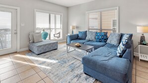 A living room with a blue sofa set, a coffee table, and a ceiling fan.