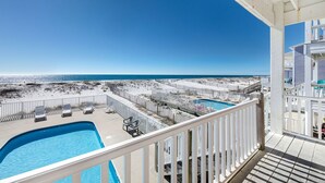 A poolside view with a clear view of the ocean and beach.