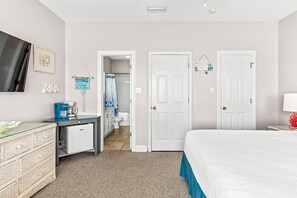 A bedroom with a bed, a desk with a coffee maker, a dresser, and a television on the wall. - Beachfront/Pool! 5 bedroom! Book Now and Save!*Sleeps 12* (Gulf Shores)