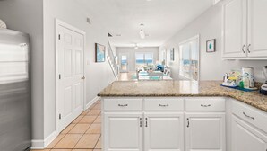 A modern kitchen with white cabinetry, granite countertops, and a view to the living area.