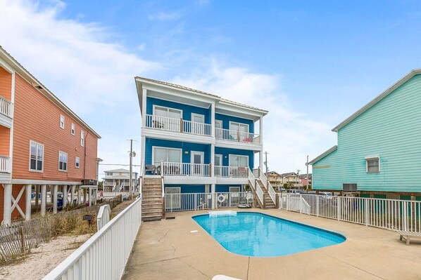 A multi-story building with a pool area, including a staircase and a fenced deck. - Beachfront/Pool! 5 bedroom! Book Now and Save!*Sleeps 12* (Gulf Shores)