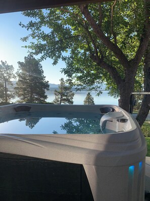Un jacuzzi con vista despejada a un lago y árboles al fondo.