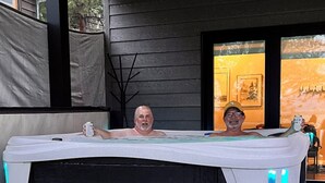 Un jacuzzi con dos personas, una sosteniendo una lata.