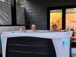 A hot tub with two people, one holding a can.