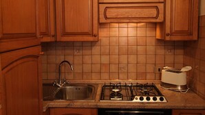 A kitchen with wooden cabinets, a stainless steel sink, a gas stove, and a toaster. - Cozy Apartment in the Historic Centre of Bellagio (Bellagio)