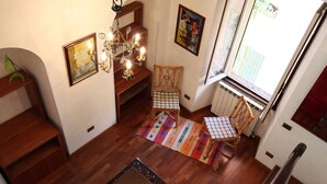A cozy interior with wooden flooring, a chandelier, a red sofa, and a window with a view. - Cozy Apartment in the Historic Centre of Bellagio (Bellagio)