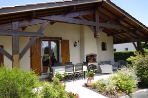 Un patio cubierto con una mesa, sillas, una chimenea y plantas en macetas.