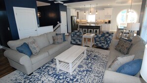 Un salon avec un canapé beige, des coussins à motifs, une table basse et un tapis aux motifs bleus et blancs.