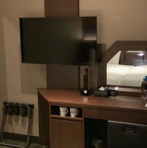 A hotel room with a flat-screen TV mounted on the wall, a bedside table with a lamp, a mirror, and a small shelf with a mug. - Nonsmoking Twin bed room Single use available  / Fukuoka Fukuoka (Fukuoka)