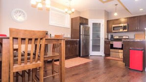 A kitchen with wooden cabinets, stainless steel appliances, and a red refrigerator. - Lower Suite Duplex - 3 Beds / 1 Bath By  Restaurants, Costco, G P Airport  (Grande Prairie)