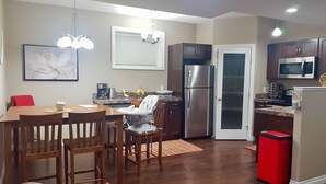 A modern kitchen with a dining area, stainless steel appliances, and a red trash bin. - Lower Suite Duplex - 3 Beds / 1 Bath By  Restaurants, Costco, G P Airport  (Grande Prairie)