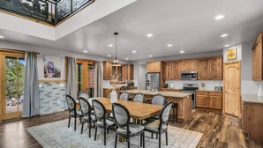 A spacious kitchen with wooden cabinets, a central island, and a dining area with a large table and chairs. - East Zion Trails Retreat: Your Gateway to Zion (Orderville)