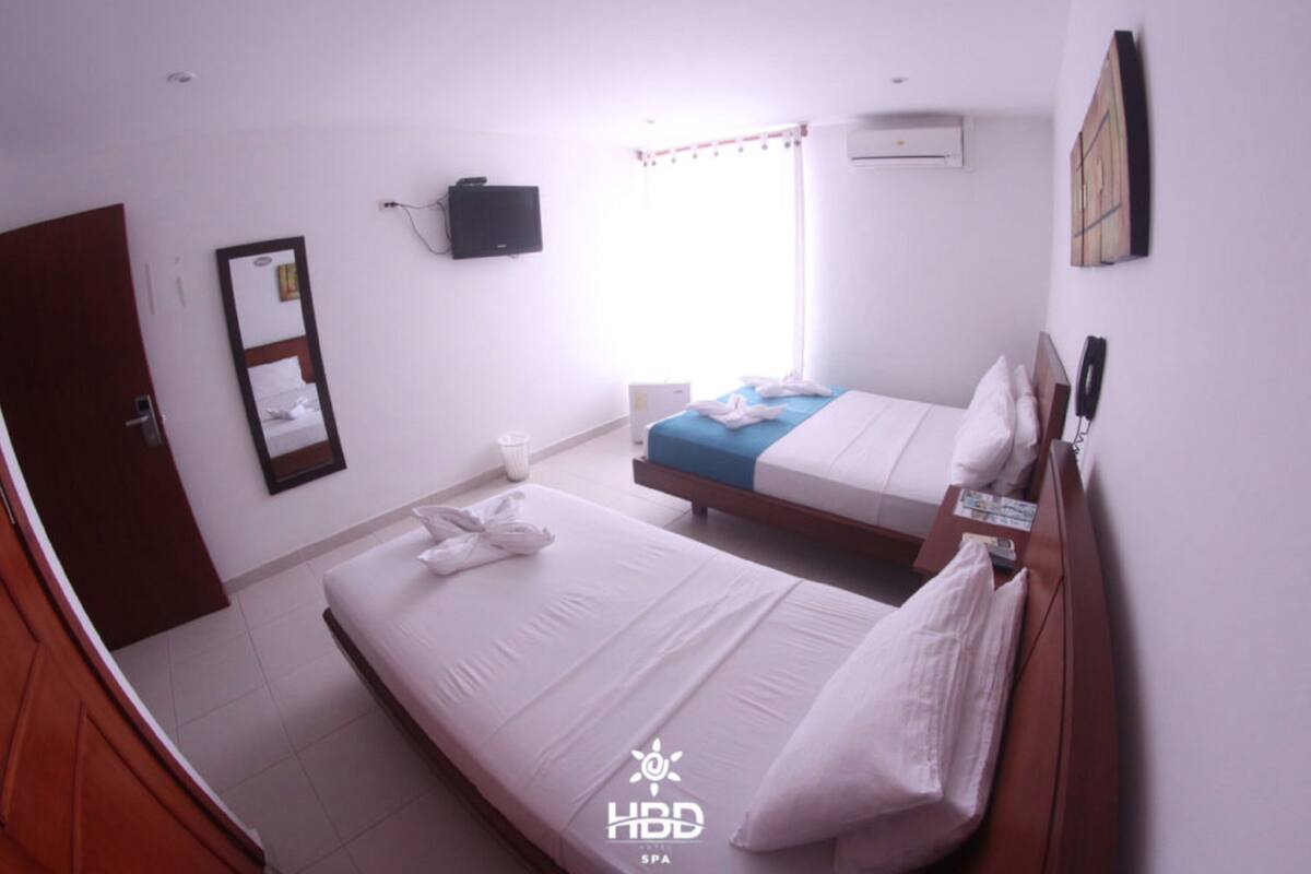 A hotel room with two beds, a TV, an air conditioner, and a mirror.