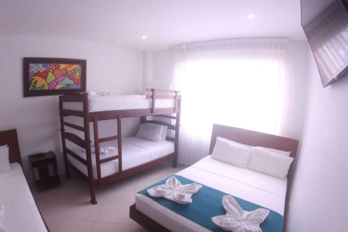 A hotel room with bunk beds, a painting on the wall, and a TV mounted on the wall.