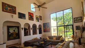 Ein geräumiges Wohnzimmer mit gemusterten Sofas, einem Couchtisch und einem Deckenventilator.