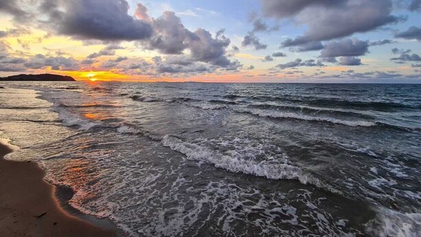 Ein Strand mit Wellen bei Sonnenuntergang.