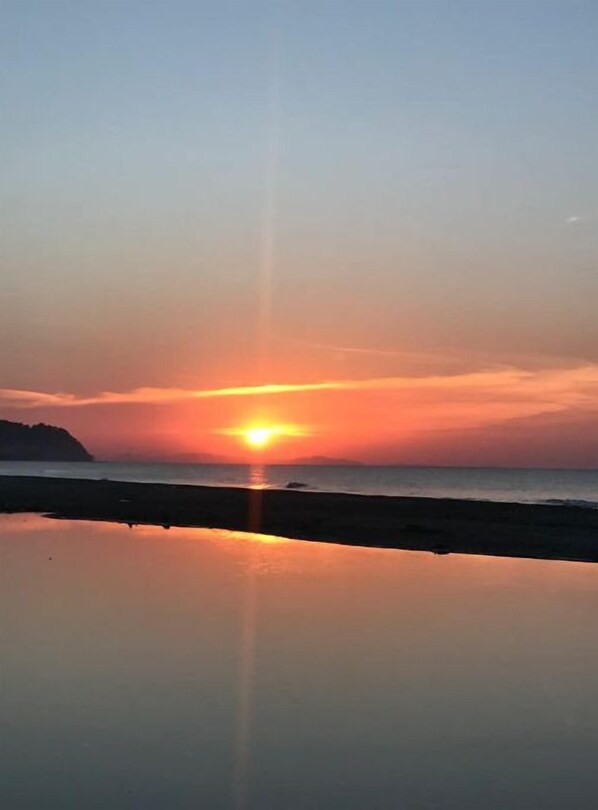 A sunset over a calm sea with a clear horizon.