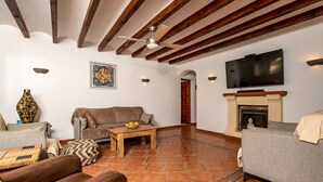 A living room with a fireplace, a television mounted above it, and a ceiling fan. - Villa for 7 (Xabia)