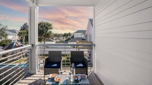 A balcony with wicker chairs, a glass table, and a view of the neighborhood. - Sleeps 20! 5 Min Walk to Beach, Private Pool & Hot Tub, 8BDR | Lyle by AvantStay (Destin)