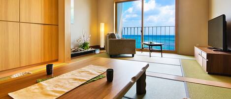 A traditional Japanese-style room with tatami flooring, a low table, a sofa, and a television.