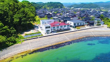 A coastal town with traditional and modern buildings, a clear waterfront, and a hilly backdrop.
