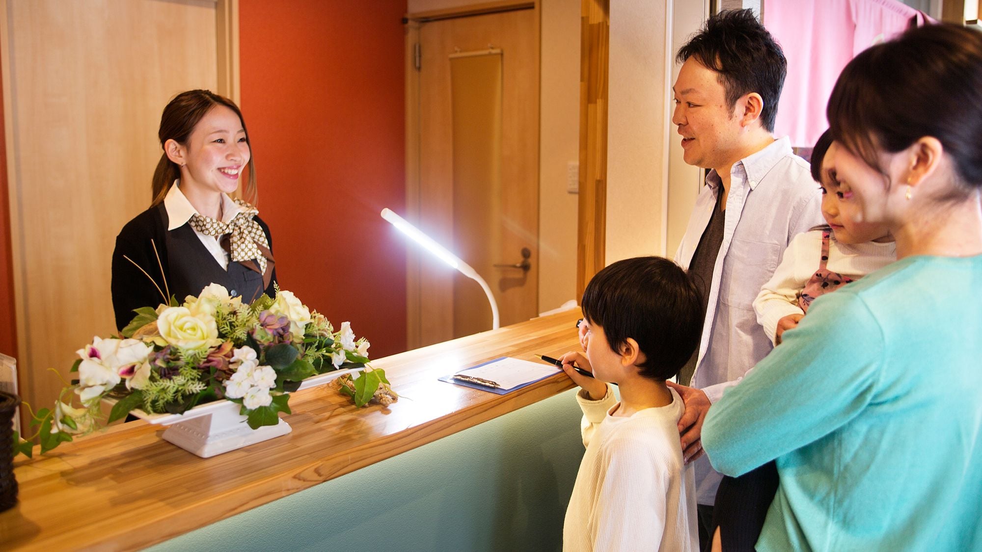 A reception desk with a floral arrangement, a notepad, and a pen.