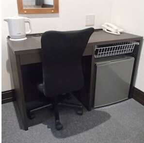 Work in comfort with a mini-fridge and a small refrigerator, a desk, and a comfortable office chair.