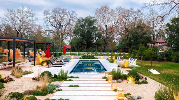 A pool area with a clear pathway leading to the pool, surrounded by lounge chairs and a covered seating area.