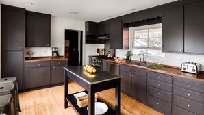 A modern kitchen with dark cabinetry, a wooden countertop, and a central island.