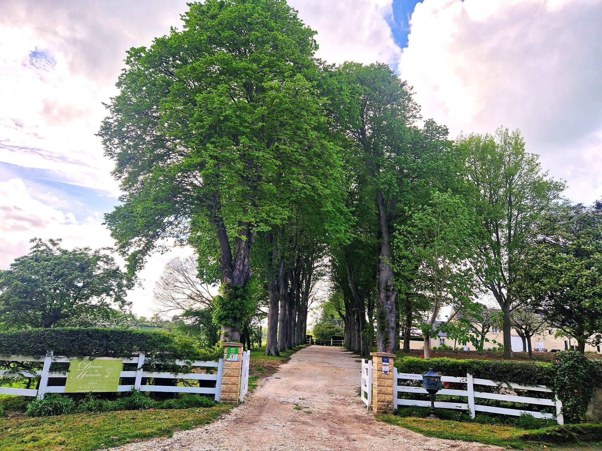 A pathway leading through a park with a white fence and a sign indicating 'Domaine Hautenville'.