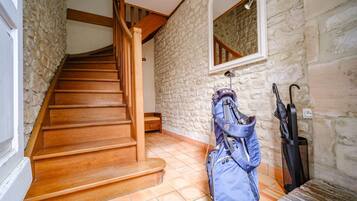 A wooden staircase with stone walls, a mirror, and a blue backpack hanging on the wall.