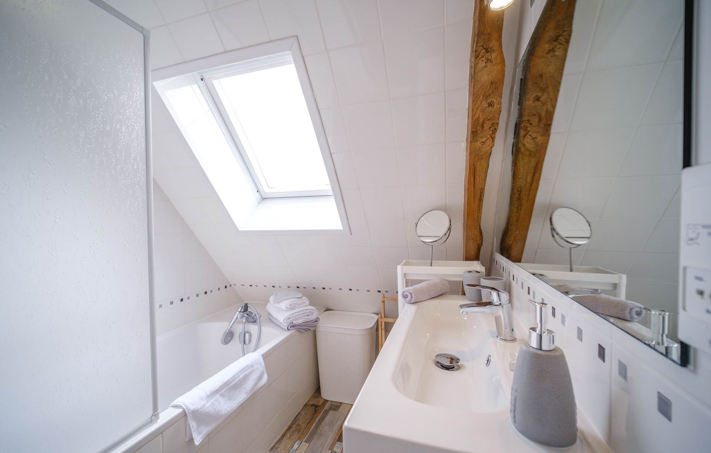 Een moderne badkamer met dakraam, ligbad, wastafel en spiegel.
