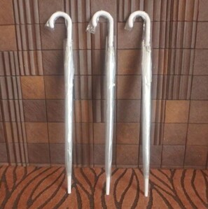 Drie metalen wandelstokken tegen een betegelde muur.