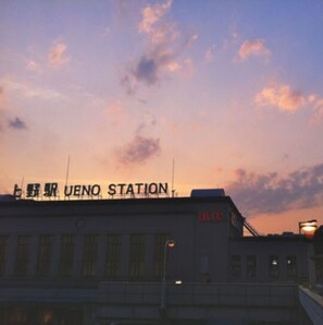 Een gebouw met borden waarop in rode letters 'UENO STATION' en 'ALICE' staat.