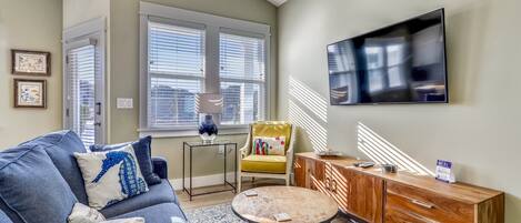 A living room with a sofa, coffee table, and a TV on the wall.