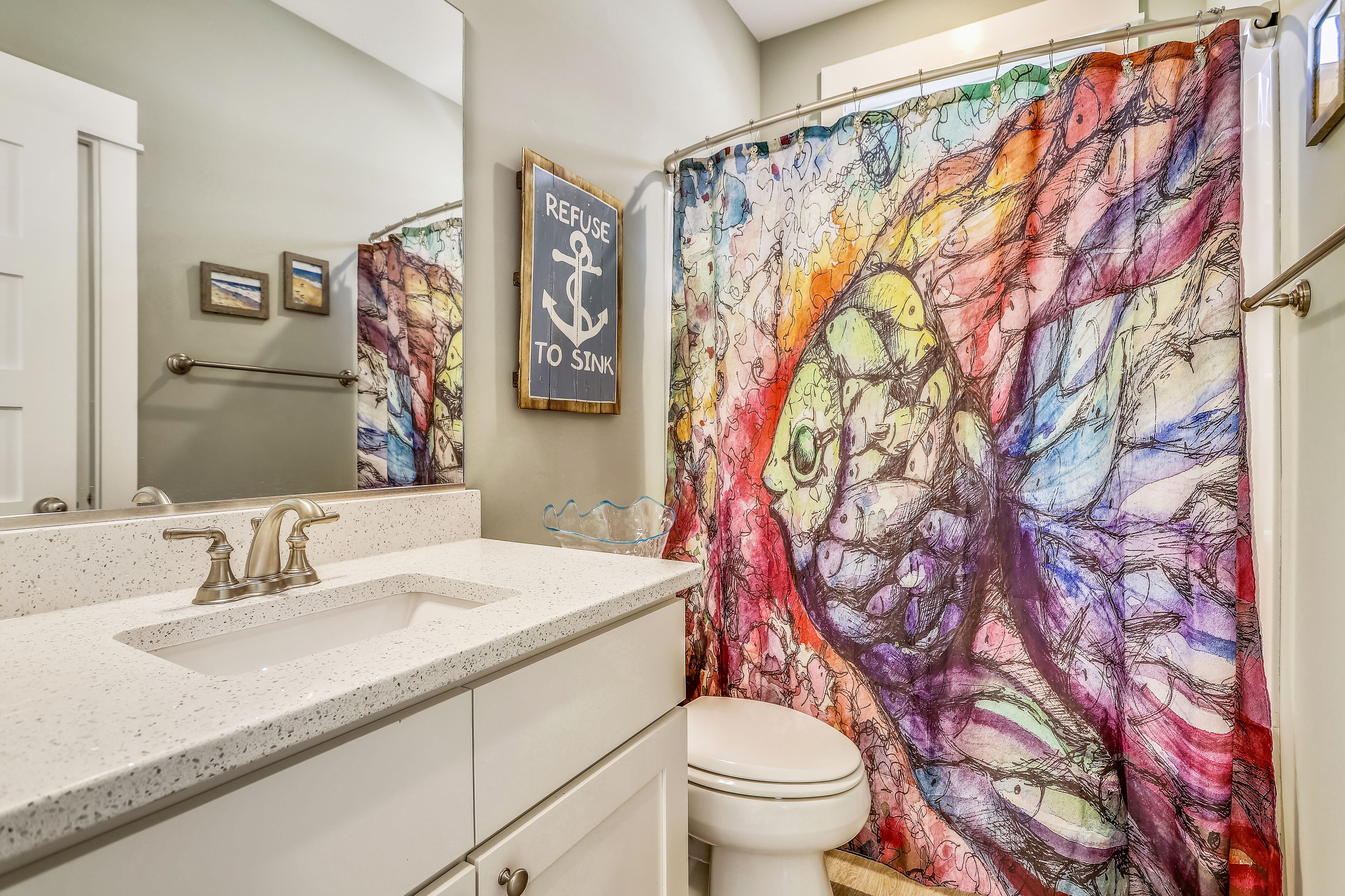 A bathroom with a colorful shower curtain, a sink, and a toilet.