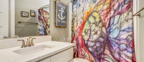 A bathroom with a colorful shower curtain, a sink, and a toilet.